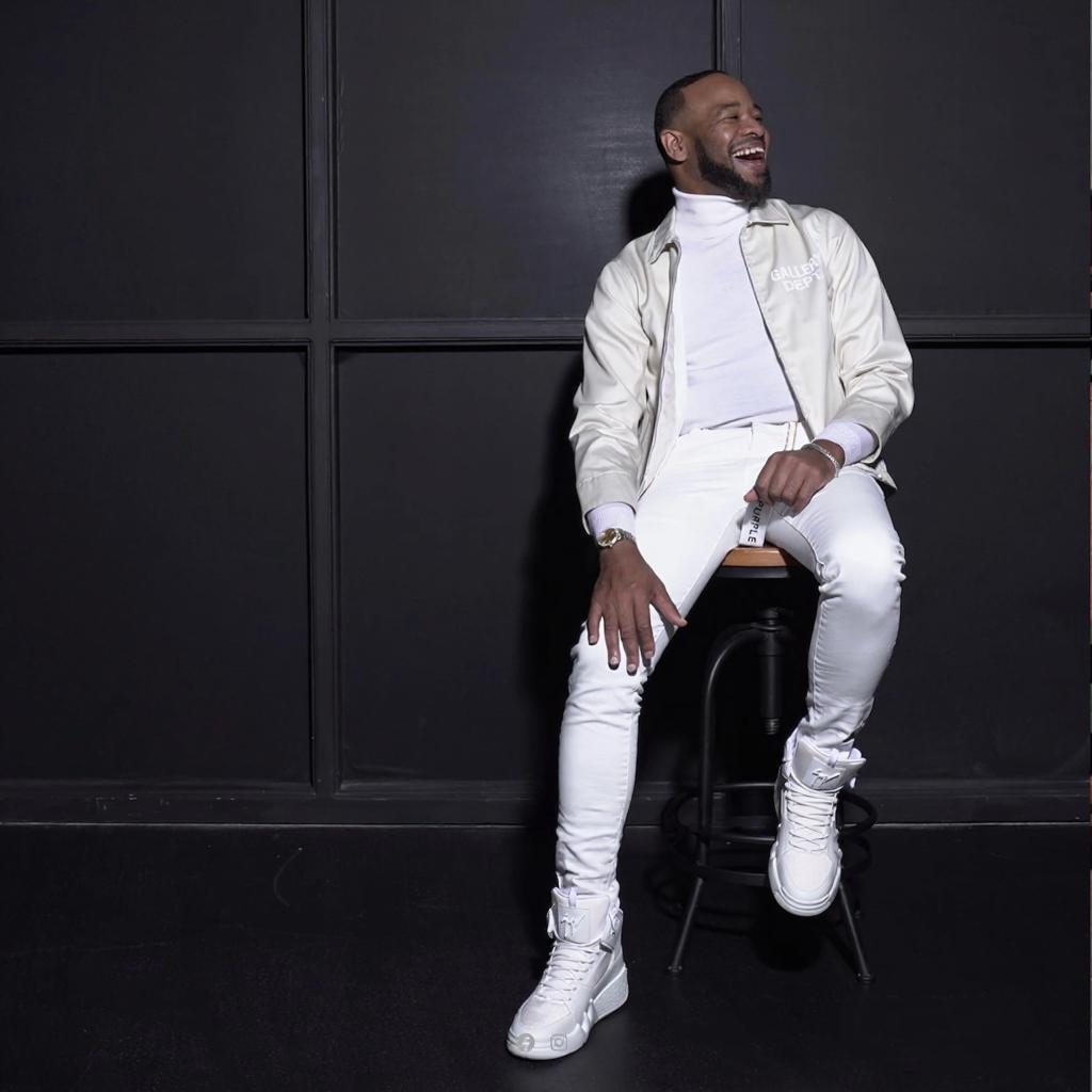 DeWayne Woods in white outfit on stool