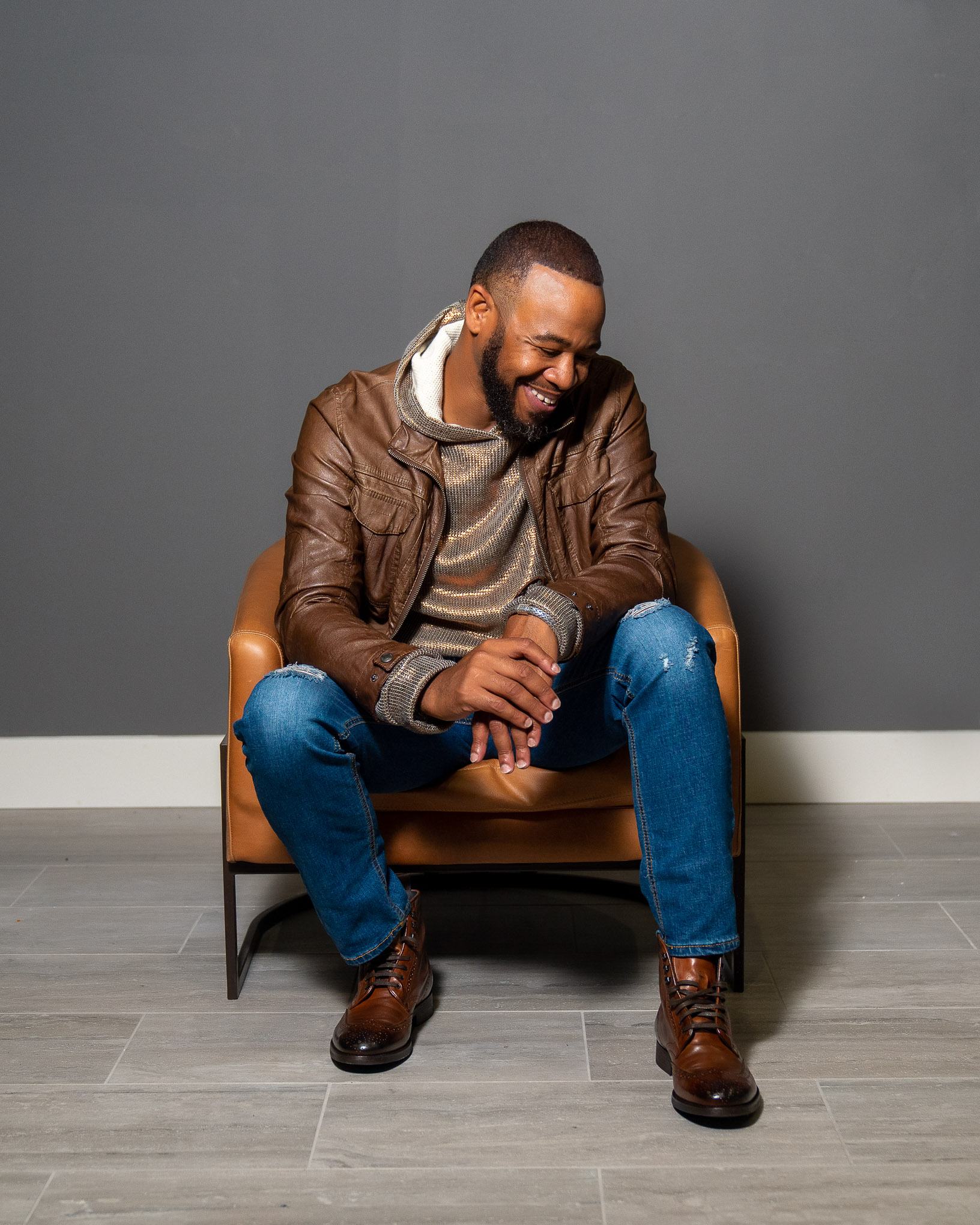 DeWayne Woods in brown leather jacket sitting